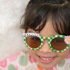 **SHIPS IN 1-2 BUSINESS DAYS** Listing is for one pair of sunglasses with personalization, and flower charm. Made to order.  Total width of flower shape on sunglasses is 5.11 inches. Frame width and height are 5.31 inches.  Toddler/ Kids sunglasses. Suitable for ages 3-8 Light to wear. Made of AC and PC material. UV 400 If you want a different color flower added, message me :) Retro Sunglasses With Tinted Lenses For Gift, Retro Sunglasses With Tinted Lenses As Gift, Retro Sunglasses With Tinted Lenses As A Gift, Trendy Personalized Sunglasses For Birthday, Custom Name Fun Sunglasses For Summer, Playful Party Sunglasses Personalized, Playful Personalized Sunglasses For Party, Personalized Playful Sunglasses For Party, Playful Multicolor Sunglasses For Birthday