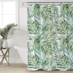 a shower curtain with green leaves on it next to a white bathtub in a bathroom