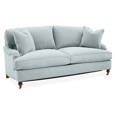 a light blue couch with pillows on the arm and back cushions, sitting in front of a white background