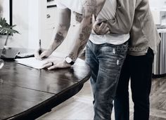 two men standing next to each other in front of a table with a laptop on it