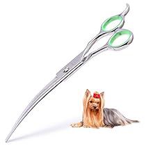 a small dog laying next to a pair of scissors on a white background with green handles