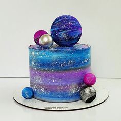 there is a cake decorated with blue, purple and silver marbles on the top