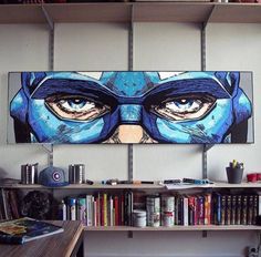 an art work is displayed on the wall above a bookshelf