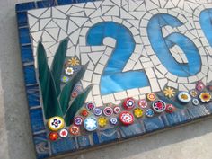 a mosaic tile sign with the number twenty two and flowers on it's side