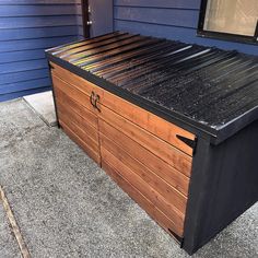 a large wooden storage box sitting on the side of a house