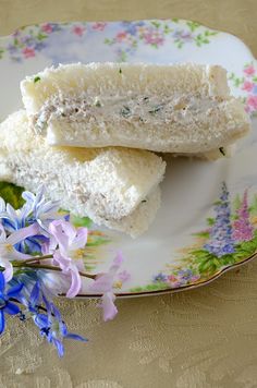 two pieces of white cake on a plate with flowers and bluebells in the background