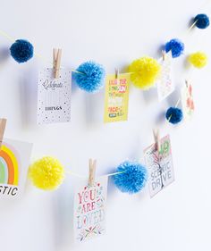 there are some cards and pom poms hanging on the clothes line