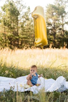 a baby sitting on a blanket with a balloon in the air