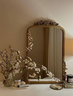 a mirror sitting on top of a table next to a vase with flowers