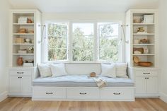 a window seat in the corner of a room with bookshelves and cabinets on either side