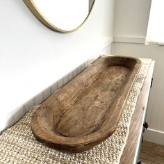 a wooden tray sitting on top of a rug next to a mirror and wall mounted faucet