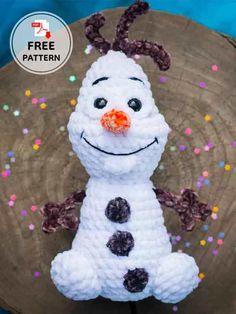 a white crocheted snowman sitting on top of a wooden plate with sprinkles