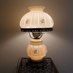 a lamp that is sitting on top of a table next to a light fixture with a glass shade over it