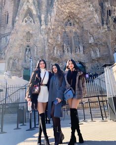 three young women are standing in front of a rock formation, posing for the camera