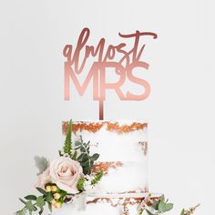 a wedding cake with the word almost mrs on top and flowers in front of it