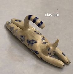 a cat figurine laying on its back with it's tail curled up