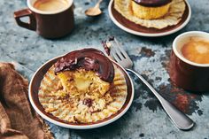 two plates with desserts on them next to cups of coffee