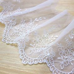 three pieces of white lace sitting on top of a wooden table