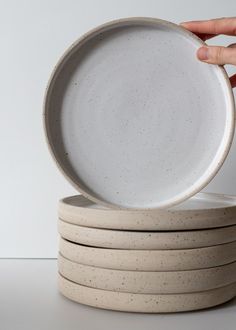 a stack of white plates sitting on top of each other in front of a person's hand