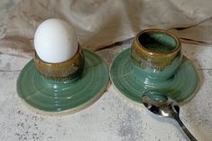 two green cups with an egg on them