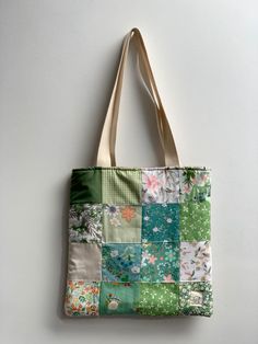 a multicolored patchwork tote bag hanging on a wall with white background