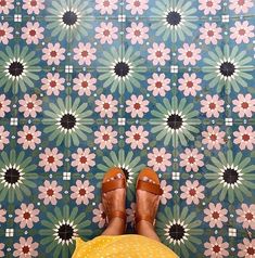 a person standing in front of a flowered wall with their feet on the ground