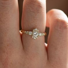 a woman's hand with a diamond ring on top of her finger, showing the center stone