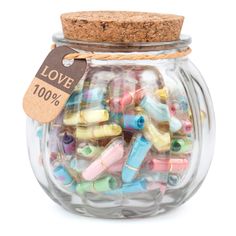 a glass jar filled with lots of colorful beads and a tag on the top that says love