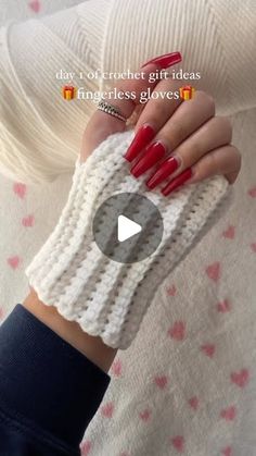 a woman with red nails holding onto a white knitted wrist warmer that is attached to her arm