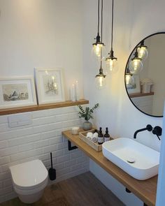 a bathroom with a sink, toilet and lights hanging above the vanity area in front of it