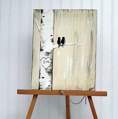 an easel with a painting on it that has two birds perched on the branch