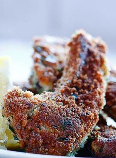 some fried food on a plate with lemon wedges