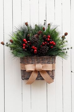 a basket filled with pine cones and evergreens on top of a white wooden wall