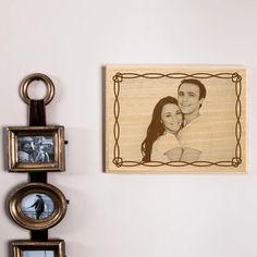 a couple's portrait is mounted on the wall next to two framed photos and a keychain