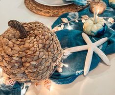 the table is set with blue linens and seashells, candles, and starfish