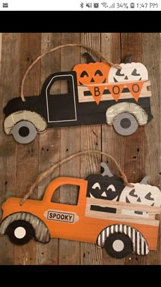 two wooden cars decorated with pumpkins and jack - o'- lanternes are hanging on a wall