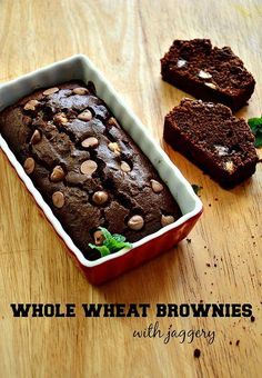 a loaf of chocolate cake sitting on top of a wooden table next to two slices of bread