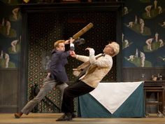 two young men are performing on stage with one holding a baseball bat and the other jumping