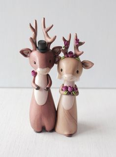 two ceramic deer figurines with antlers on their heads and flowers in their hair