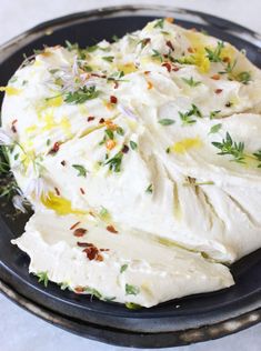 a black plate topped with whipped cream and herbs