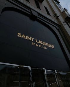 the entrance to saint laurent pa paris is lit up at night with gold lettering on it