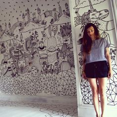 a woman standing in front of a wall with drawings on it