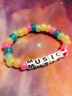 a bracelet with the word music written on it and beads attached to it, sitting on top of a galaxy background