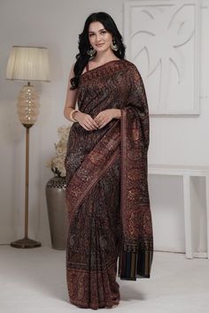 Smoky Black Kani Jamawar saree in silk fabric has Kani Jamawar weaving over the body exhibiting paisleys and flowers in zigzag pattern over the body. The border and pallu has paisleys laid in linear pattern in beautiful color combinations. A touch of zari woven with the threads adds a touch of sheen to the saree. It is accompanied with black blouse piece that has Kani weaving in scattered paisley pattern. The design inspiration for this Pashmina Silk saree is drawn from the heritage weaves of ancient Pashmina shawls from our history that dates back to the Mughal era.  Kani is an ancient and traditional craft of Kashmir that is traced back to 3000 BC. We try to preserve the uniqueness and charm of this craft and demonstrate a highest level of craftsmanship and finest work of art that has be Luxury Traditional Wear With Zari Weaving For Celebrations, Luxury Art Silk Pre-draped Saree With Zari Weaving, Luxury Pre-draped Saree With Zari Weaving In Dola Silk, Cheap Elegant Traditional Wear With Zari Weaving, Luxury Traditional Wear With Zari Weaving In Raw Silk, Luxury Jamawar Traditional Wear With Zari Weaving, Luxury Jamawar Fabric With Zari Weaving, Luxury Traditional Wear In Raw Silk With Zari Weaving, Jamawar Saree