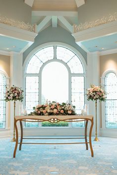 a table with flowers and candles on it in front of a large window at a wedding