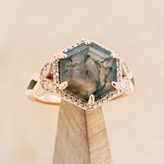 a gold ring with a large green stone surrounded by small white and brown diamonds on top