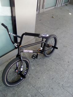 a black bike parked on the sidewalk next to a building