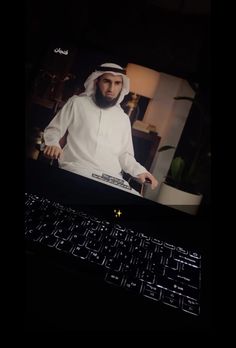 a man wearing a white outfit is on the screen of a laptop computer and it's keyboard