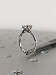 a diamond ring sitting on top of a metal surface with drops of water around it