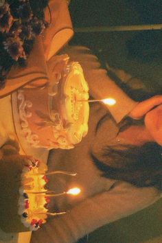 a man sitting in front of a cake with lit candles on it's side